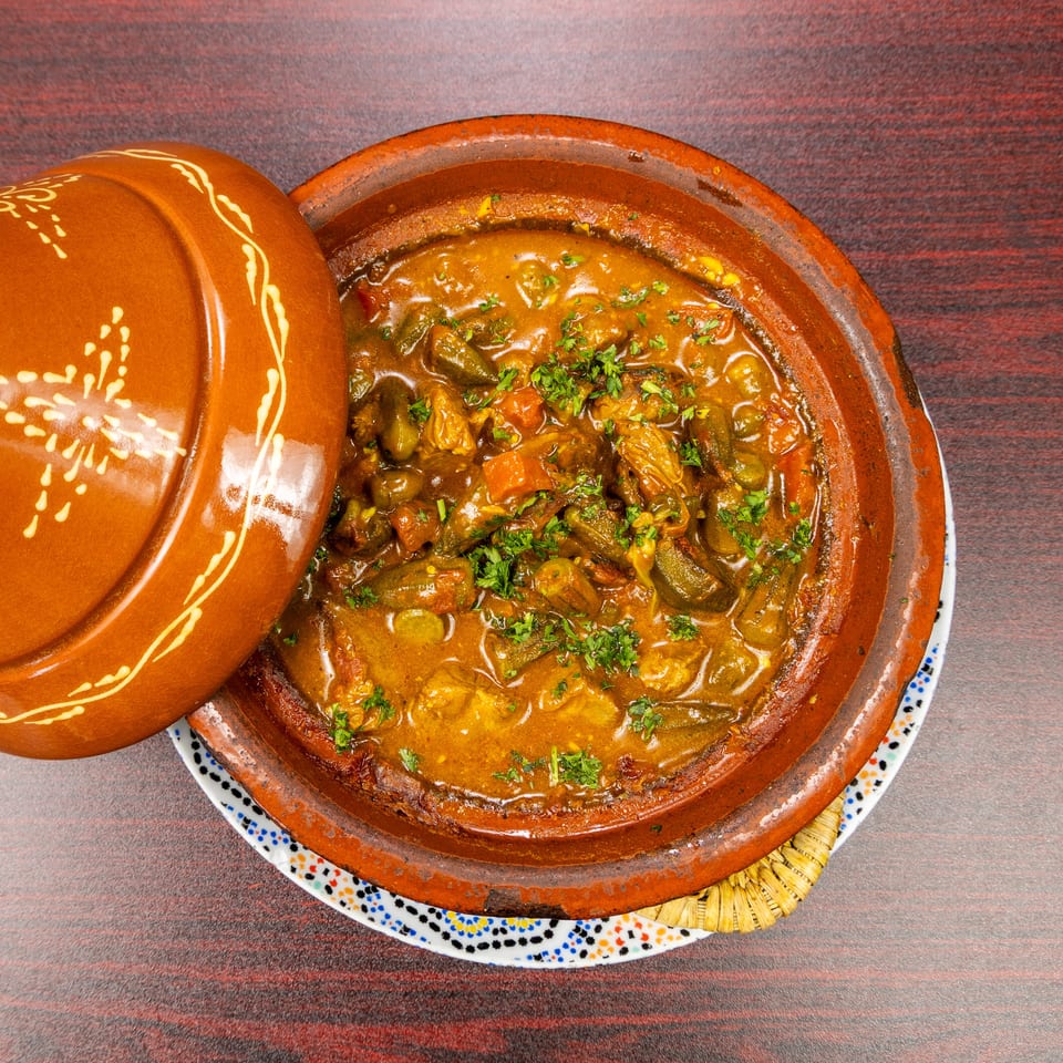 Moroccan tagine filled with richly spiced vegetables and meat, garnished with fresh herbs in a traditional terracotta dish.